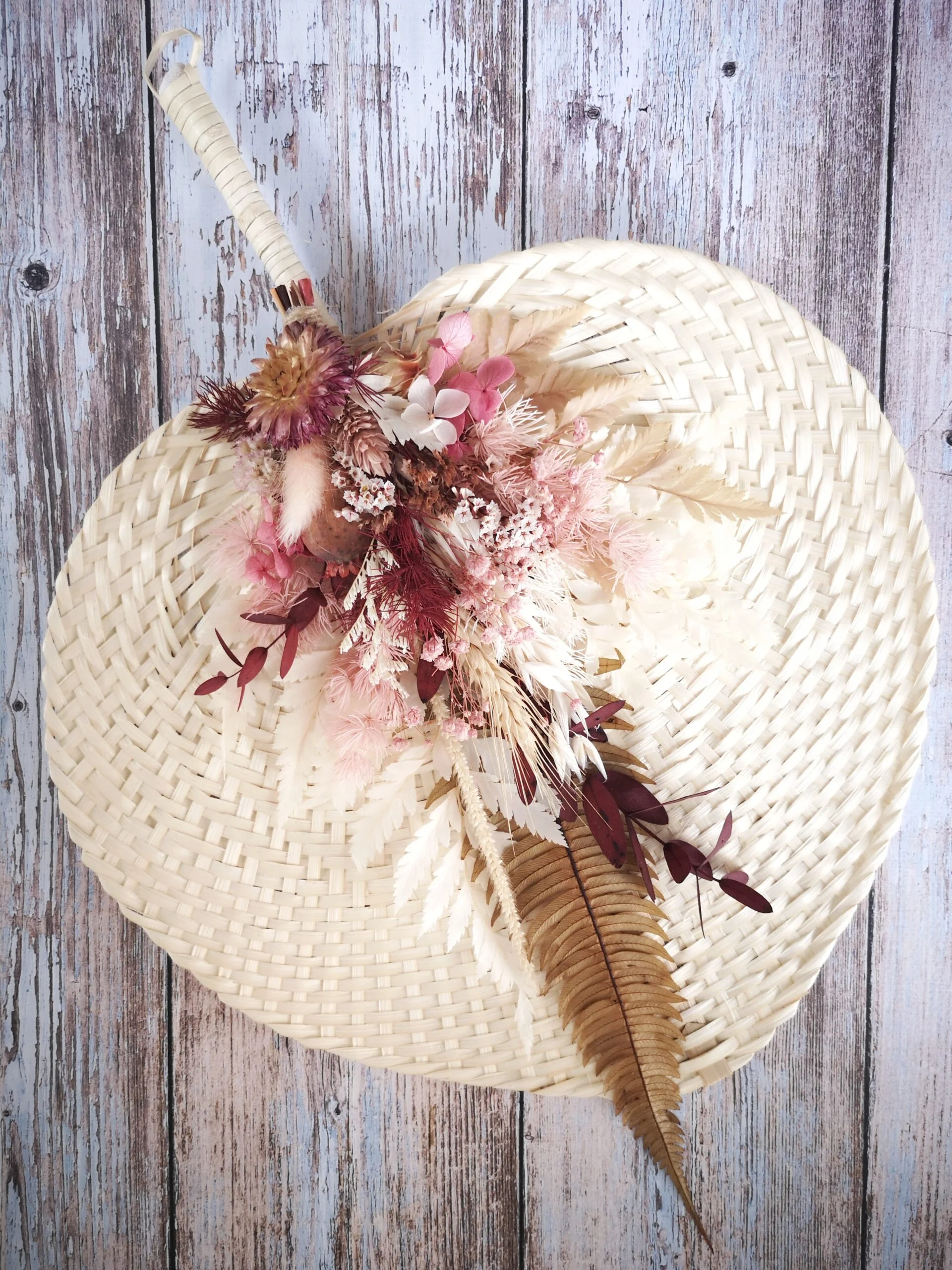 Eventail en bambou orné de fleurs séchées. Coloris rose et beige. Décoration fleurie à poser ou suspendre