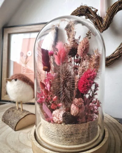 Cloche de fleurs séchées dans des tons rose et marron.