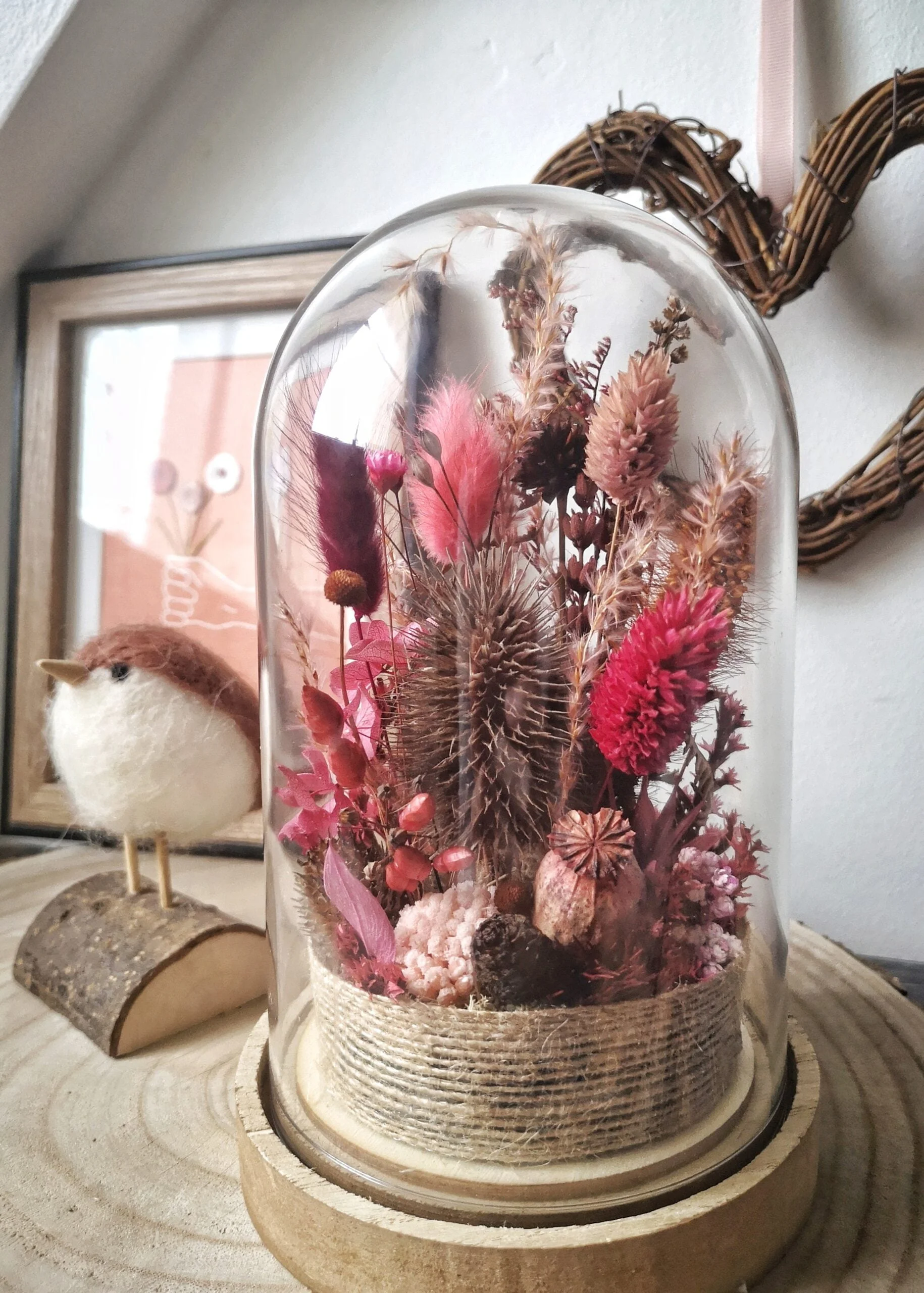 Cloche de fleurs séchées dans des tons rose et marron.