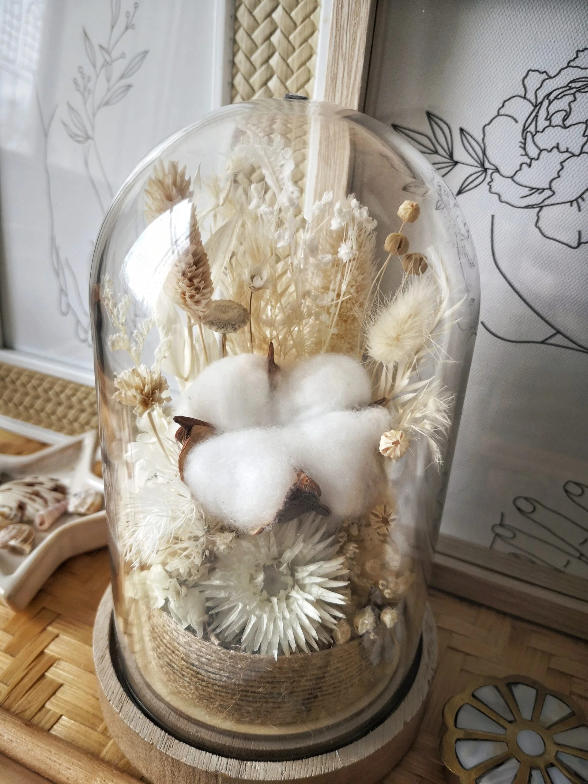 Cloche de fleurs séchées dans les tons blanc, crème et neutre. Idéale pour une décoration de mariage bohème ou pour une idée de cadeau pour un 1er anniversaire de mariage (noces de coton) grâce à sa fleur de coton située au centre de la cloche.