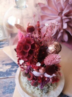 Cloche de fleurs séchées dans des tons rose, rouge et cuivrées. Dans cet écrin en verre est venu se nicher un petit jardin romantique aux couleurs rose et rouge illuminé par des touches cuivrées.