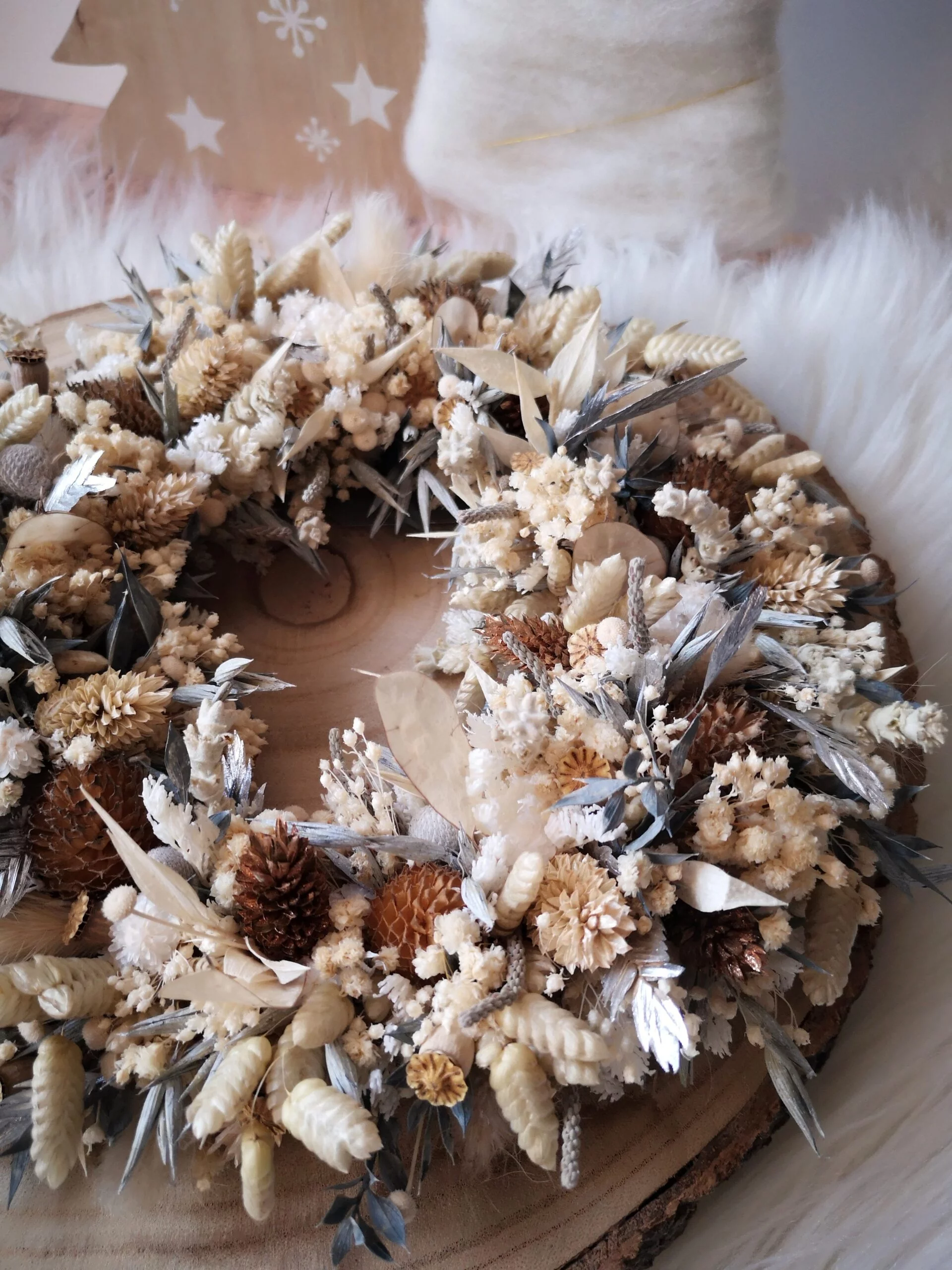 Couronne murale de fleurs séchées dans les tons blanc, gris, brun et métallisé. Des teintes hivernales douces et féeriques.