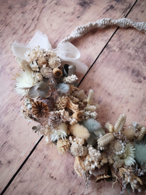 Couronne murale en macramé avec des fleurs séchées dans les tons neutres et verts. Décoration douce et tendance.