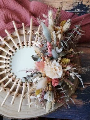 Petit miroir orné de fleurs séchées dans les tons rose, jaune, vert et neutre. Création artisanale.