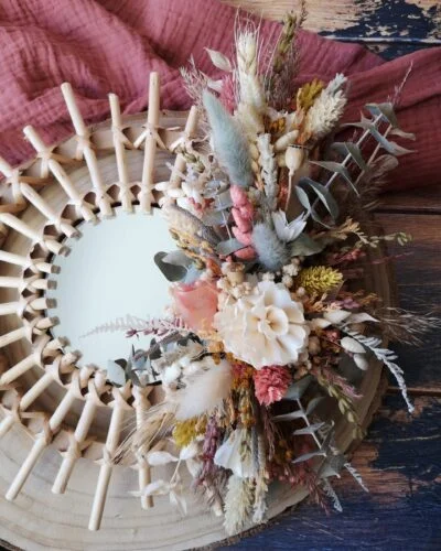 Petit miroir orné de fleurs séchées dans les tons rose, jaune, vert et neutre. Création artisanale.