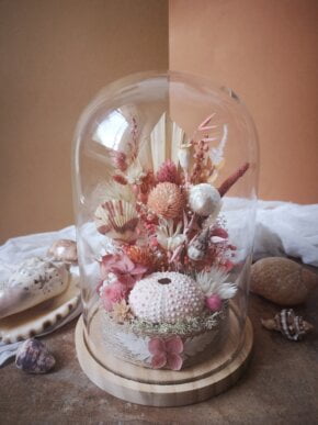 Fleurs séchées sous une cloche en verre, coloris rose, corail et blanc.