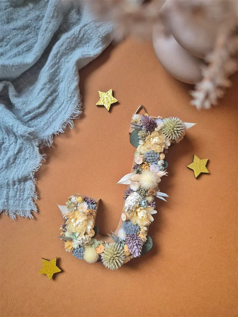 Lettre "J" ornée de fleurs séchées dans les tons blanc, bleu, vert