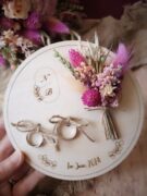 Amenez vos alliances avec élégance le jour de votre mariage avec ce porte alliances en bois orné de fleurs séchées