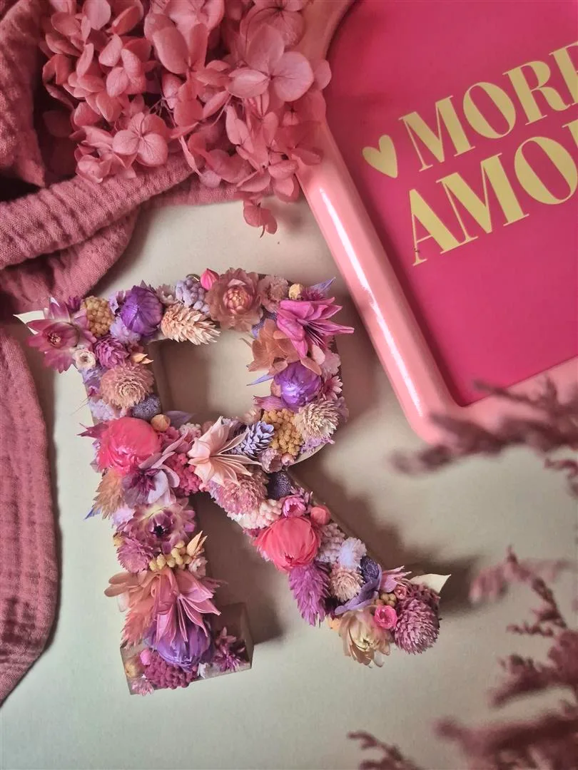 Lettre “R” ornée de fleurs séchées dans les tons rose, violet et pêche
